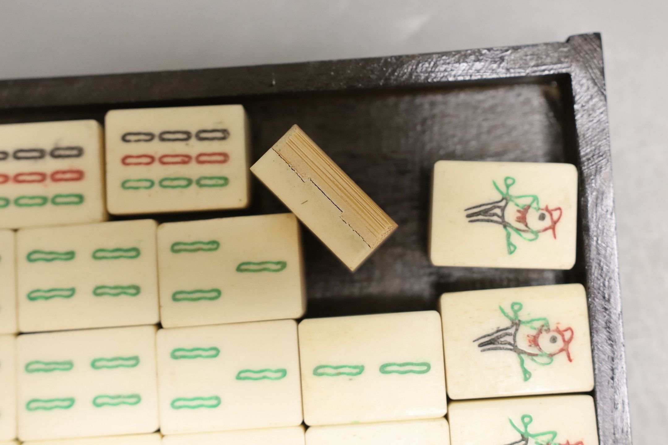 A Chinese boxed mahjong set, bone and bamboo gaming pieces, 24.5 cms wide x 16cms high.